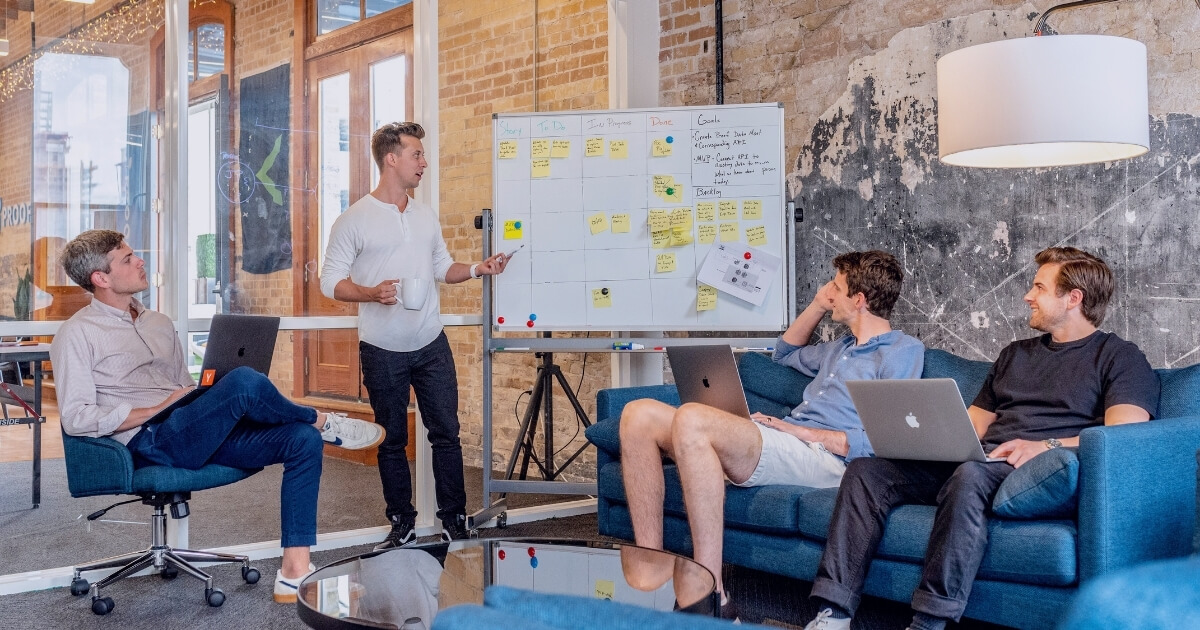 Four men in a meeting planning on a whiteboard